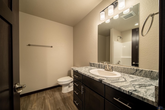 bathroom featuring hardwood / wood-style flooring, vanity, walk in shower, and toilet