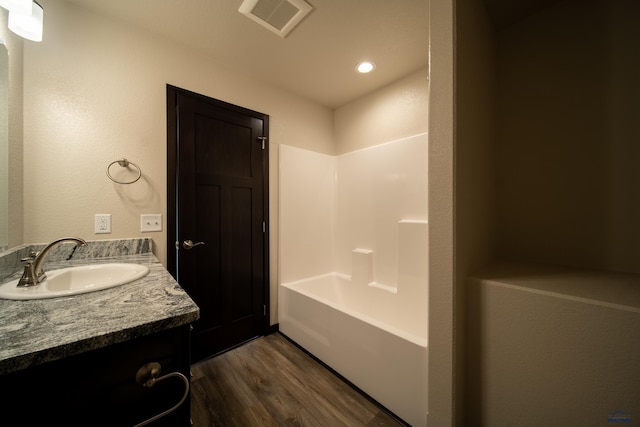 bathroom with hardwood / wood-style flooring, washtub / shower combination, and vanity