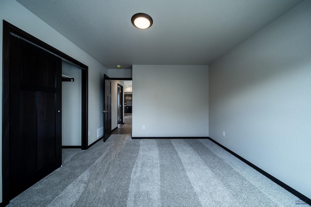 unfurnished room featuring dark colored carpet and a textured ceiling