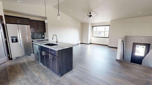 kitchen featuring sink, appliances with stainless steel finishes, a kitchen island with sink, light stone counters, and decorative light fixtures