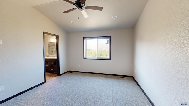 unfurnished bedroom with ceiling fan, ensuite bath, lofted ceiling, and light carpet