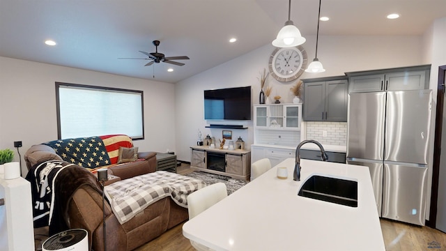 kitchen featuring gray cabinetry, hanging light fixtures, sink, vaulted ceiling, and stainless steel refrigerator