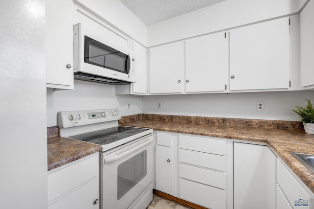 kitchen with white cabinets, white appliances, and a textured ceiling