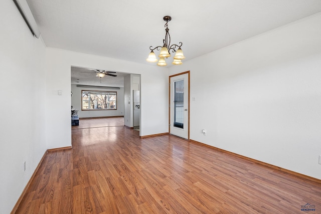 spare room with ceiling fan with notable chandelier, wood-type flooring, and crown molding