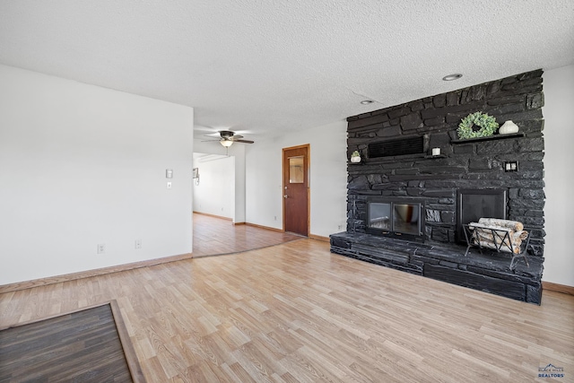 unfurnished living room with ceiling fan, a fireplace, hardwood / wood-style floors, and a textured ceiling