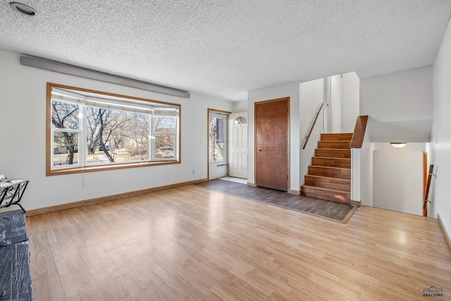 unfurnished living room featuring light wood-type flooring and a textured ceiling