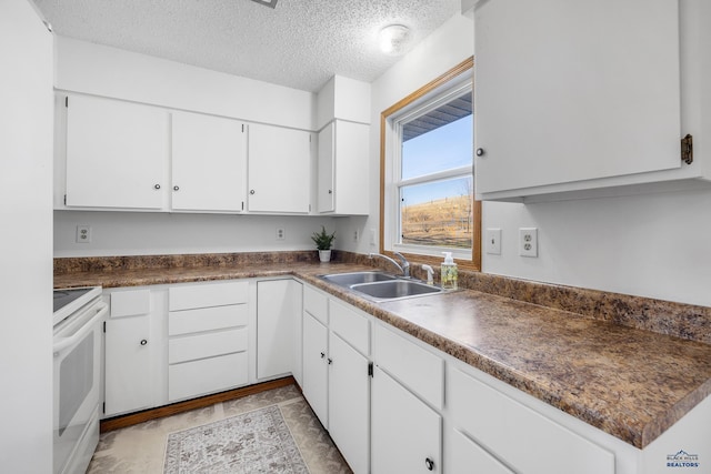 kitchen with a textured ceiling, white cabinetry, sink, and white stove