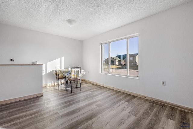 unfurnished room with hardwood / wood-style floors and a textured ceiling