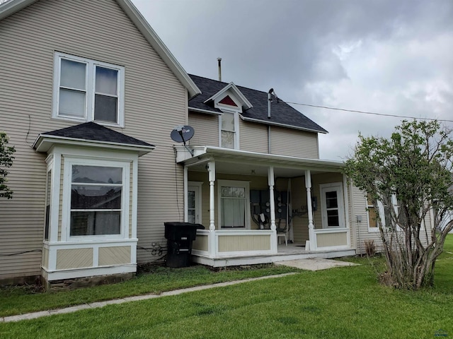 back of house with covered porch and a yard