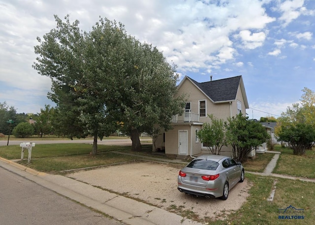 view of front of home featuring a front yard and a balcony