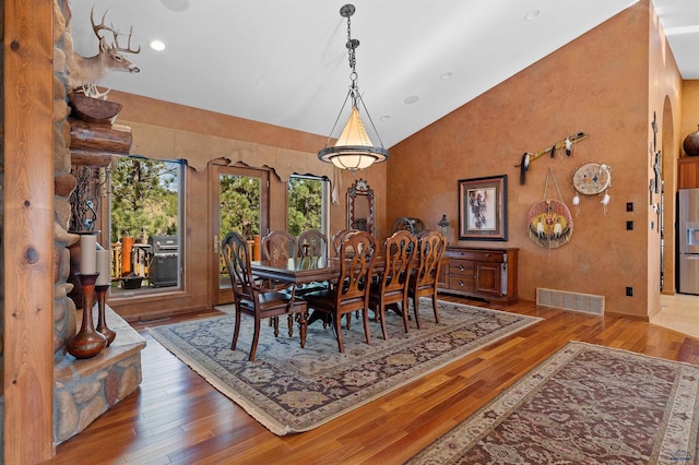 dining room with high vaulted ceiling and hardwood / wood-style flooring