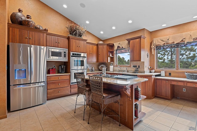 kitchen featuring vaulted ceiling, tasteful backsplash, light tile patterned flooring, a kitchen bar, and stainless steel appliances