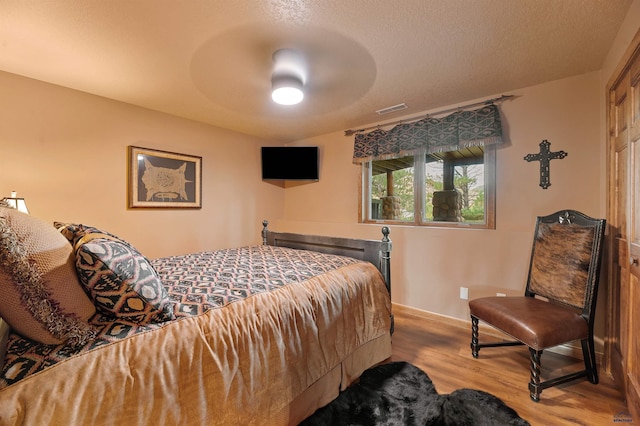 bedroom with ceiling fan, a textured ceiling, and light wood-type flooring