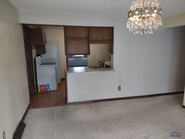 kitchen with sink, carpet, white fridge, stove, and a notable chandelier