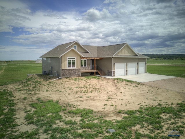 craftsman-style home featuring a rural view, a front lawn, cooling unit, a garage, and a porch