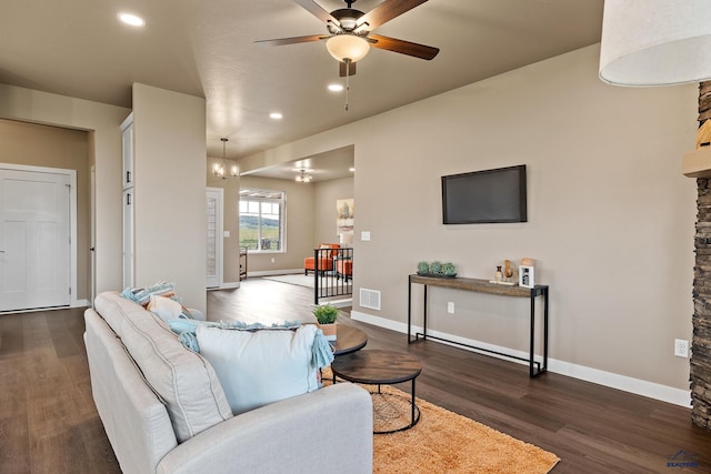 living room with ceiling fan with notable chandelier and dark hardwood / wood-style floors