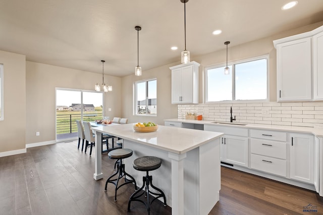 kitchen with sink, white cabinets, dark wood-type flooring, and a kitchen island