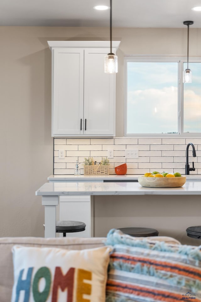 interior space with tasteful backsplash, white cabinetry, and hanging light fixtures