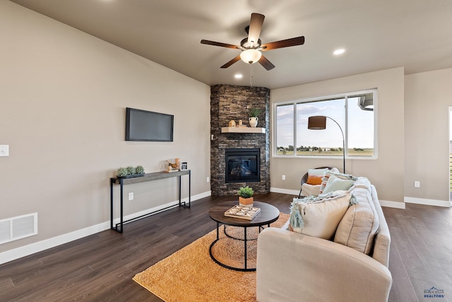 living room with a fireplace, ceiling fan, and dark wood-type flooring