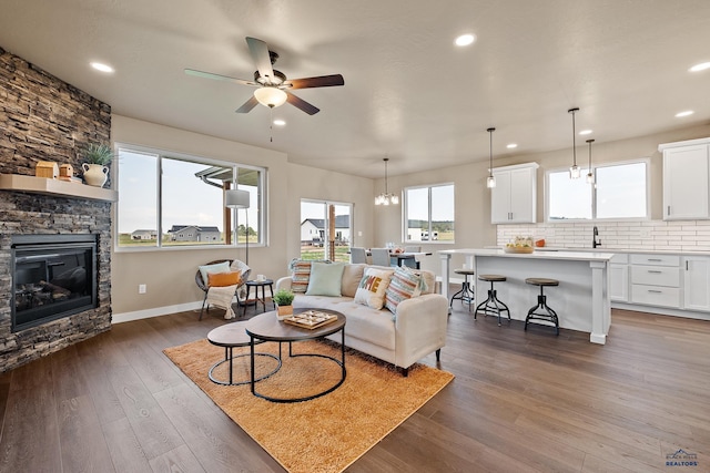 living room with a fireplace, ceiling fan, and dark hardwood / wood-style flooring