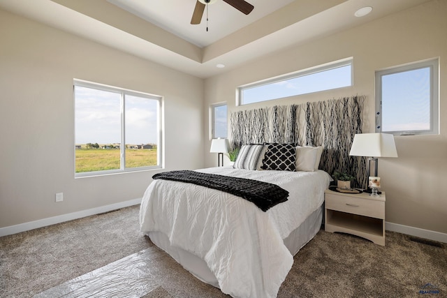 carpeted bedroom with a tray ceiling and ceiling fan