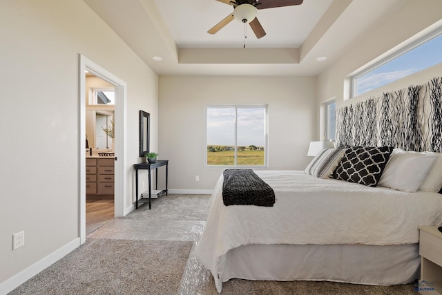 bedroom with connected bathroom, multiple windows, ceiling fan, and light colored carpet