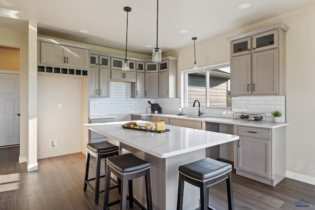 kitchen with pendant lighting, sink, dark hardwood / wood-style floors, tasteful backsplash, and a kitchen island