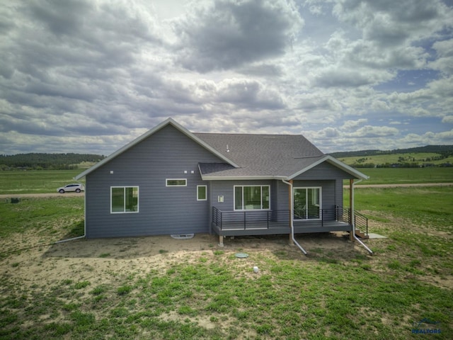 back of property with a rural view and a yard