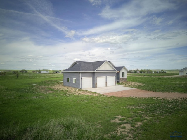 exterior space featuring a yard, a rural view, and a garage