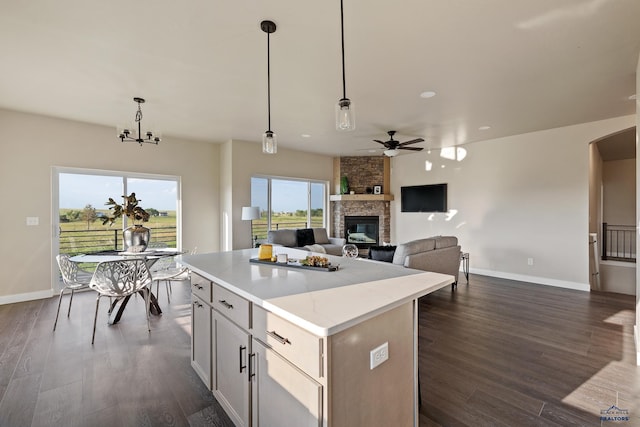 kitchen with a fireplace, pendant lighting, dark hardwood / wood-style flooring, and a kitchen island