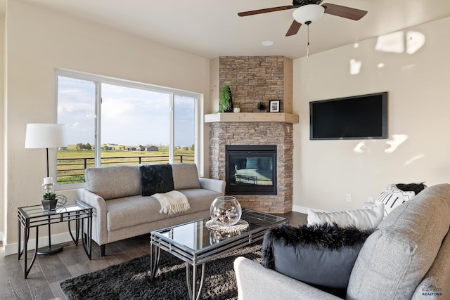 living room featuring ceiling fan, a fireplace, and dark wood-type flooring