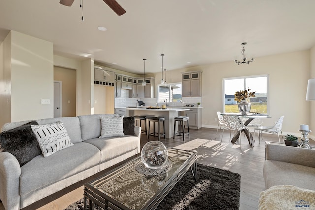 living room with ceiling fan with notable chandelier and light wood-type flooring