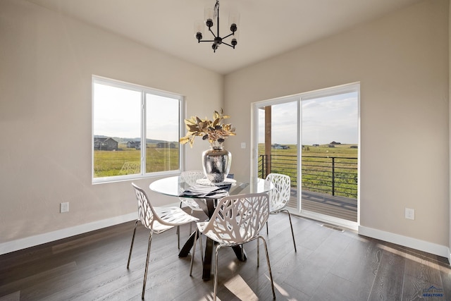 dining space with dark hardwood / wood-style flooring and a notable chandelier