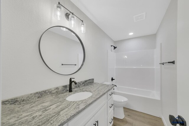 full bathroom featuring hardwood / wood-style floors, vanity, toilet, and tub / shower combination