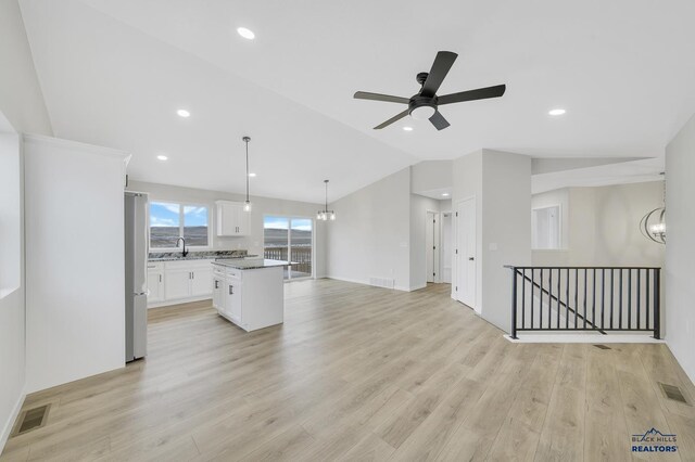 kitchen with white cabinetry, a kitchen island, lofted ceiling, and light hardwood / wood-style flooring