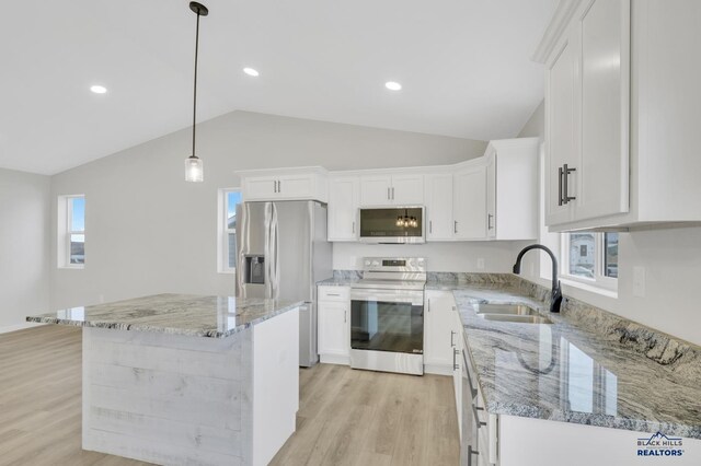 kitchen featuring white cabinets, appliances with stainless steel finishes, vaulted ceiling, and a kitchen island