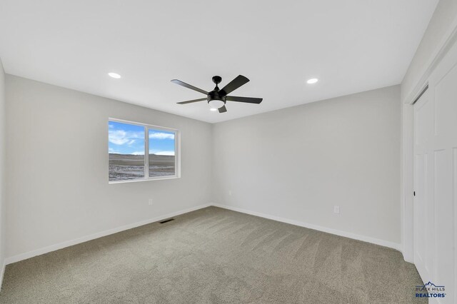 carpeted spare room featuring ceiling fan