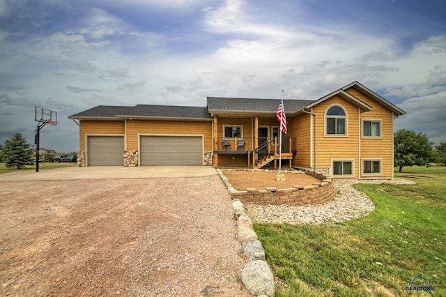 view of front of property with a garage, covered porch, and a front yard