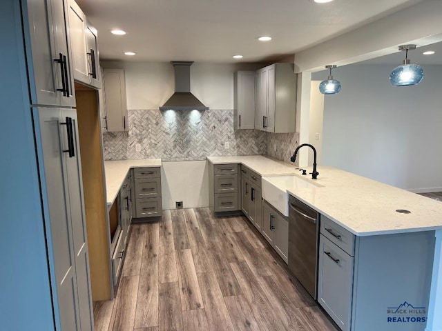 kitchen with kitchen peninsula, stainless steel dishwasher, hanging light fixtures, and wall chimney range hood