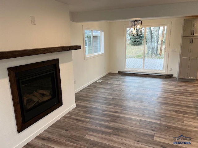 6920 Long View Rd, Rapid City, SD 57703 - unfurnished living room featuring plenty of natural light, a chandelier, a glass covered fireplace, and dark wood finished floors