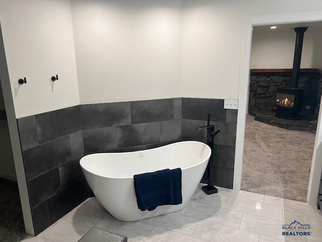 bathroom featuring a tub, tile walls, and a wood stove