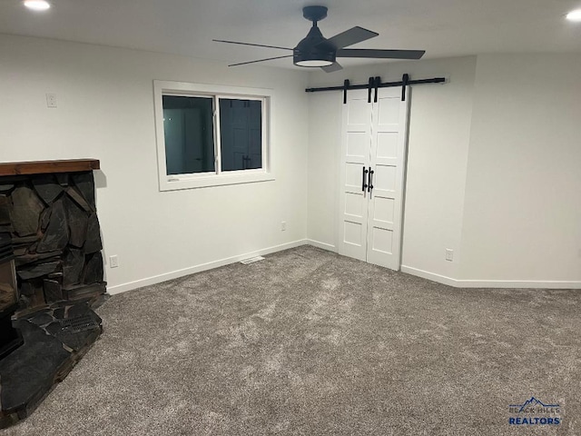6920 Long View Rd, Rapid City, SD 57703 - unfurnished living room featuring a barn door, ceiling fan, and dark colored carpet