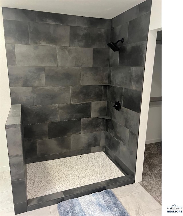 bathroom with a tile shower and tile patterned floors