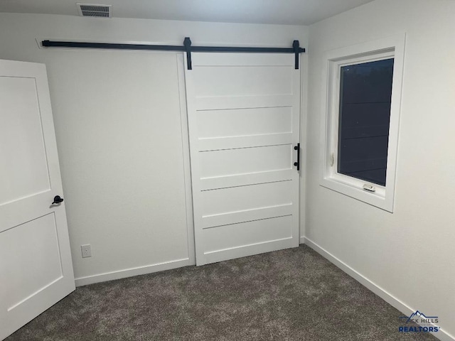 interior space with a barn door and dark carpet