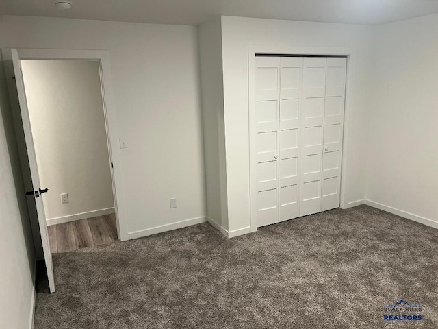 unfurnished bedroom with dark colored carpet and a closet