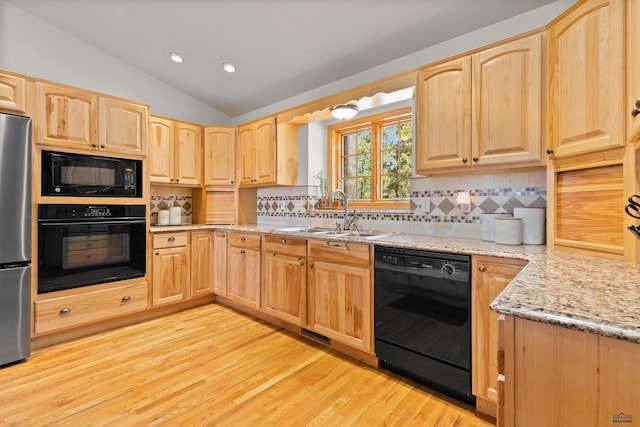 kitchen featuring decorative backsplash, light wood-type flooring, vaulted ceiling, sink, and black appliances