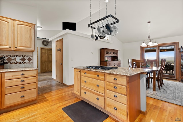 kitchen with light brown cabinetry, pendant lighting, light hardwood / wood-style flooring, a notable chandelier, and stainless steel gas stovetop