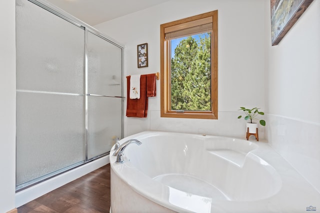 bathroom with wood-type flooring and shower with separate bathtub