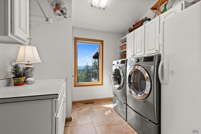 washroom featuring washer and clothes dryer, light tile patterned floors, and cabinets