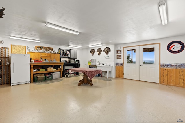 garage with wood walls, french doors, and white refrigerator